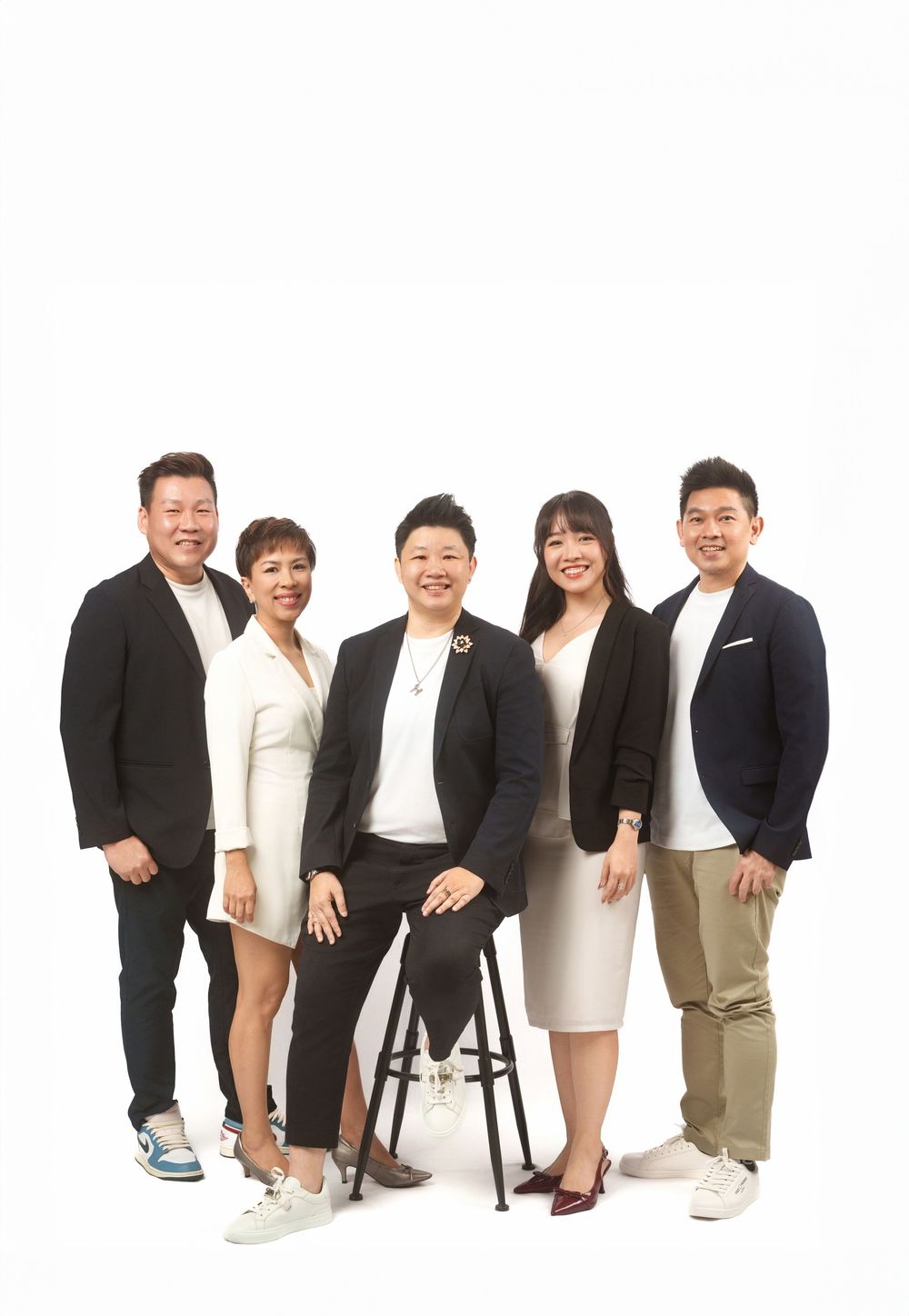 A group of people in business attire sitting and standing together against a white background for a professional photo.