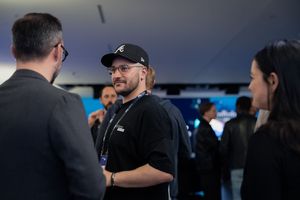 Casual networking scene at a technology conference with branded backdrop.