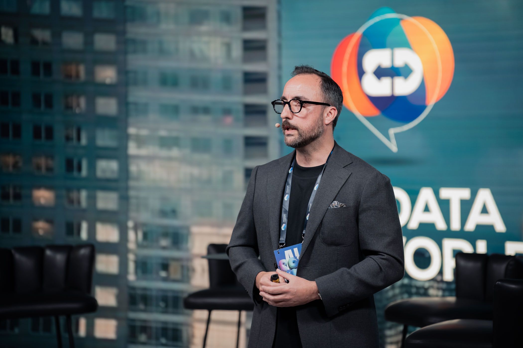 Professional speaker at data conference with corporate branding in background.