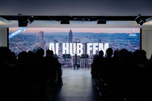 Silhouetted audience watching AI Hub presentation with city skyline backdrop.