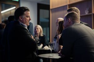 Business professionals engaged in discussion at a dimly lit networking event.