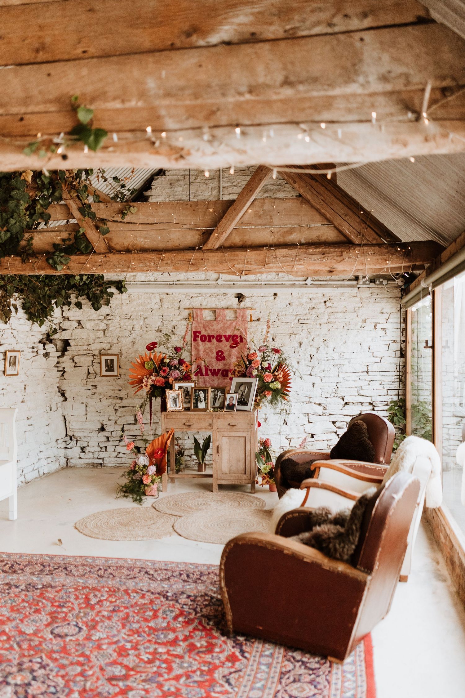 Cozy industrial loft space with exposed brick walls, wooden beams, pink rugs and vintage leather furniture.