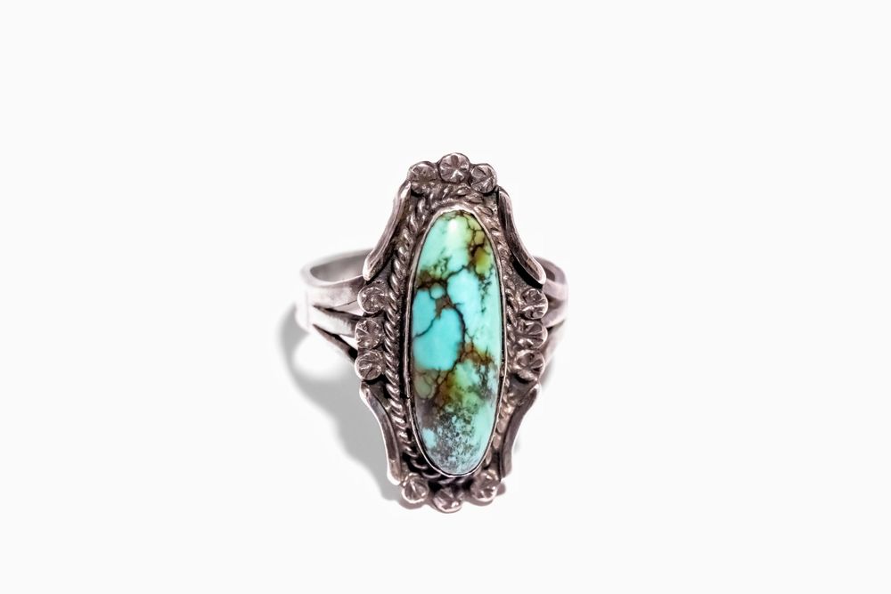 Sterling silver ring featuring turquoise stone with ornate filigree border design.