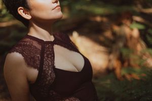 Close-up portrait showing lace details of a burgundy dress in dappled sunlight.