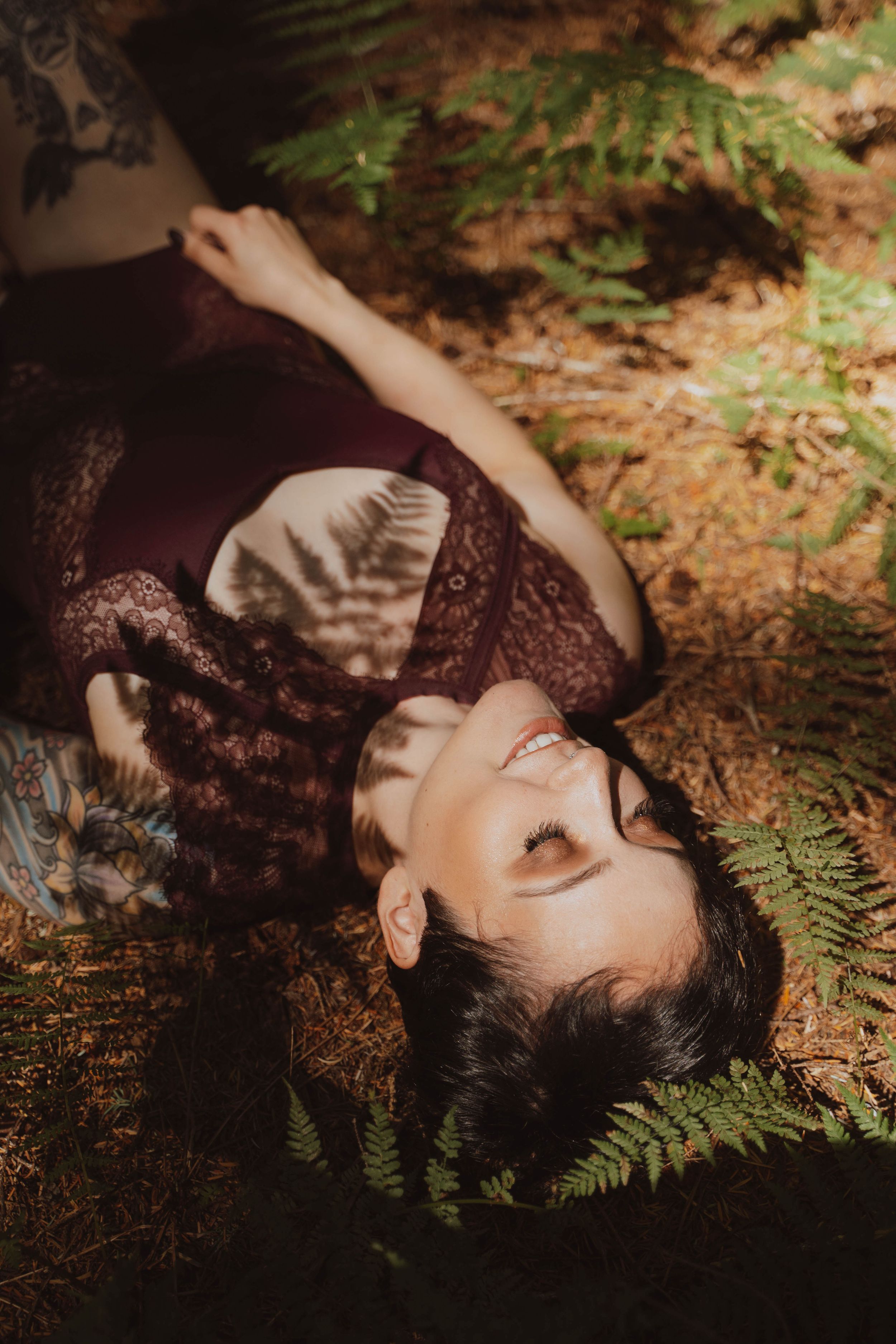 Artistic portrait among ferns with soft natural lighting and shadows.
