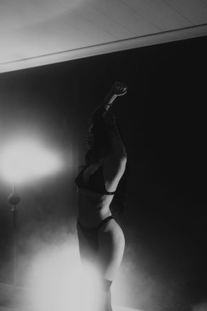 Artistic black and white silhouette of a figure in dramatic lighting with arms raised.