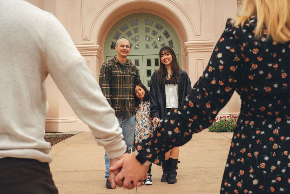 mom and dad holding hands while children smile in-between them