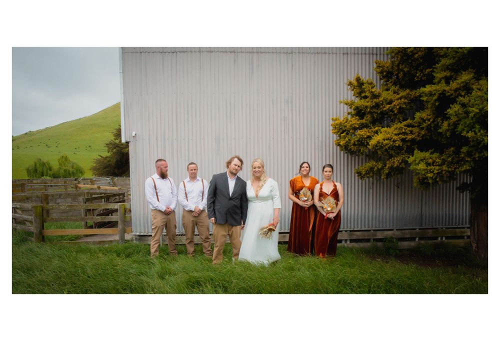 Wedding photo of wedding party in from of a wool shed on a farm.