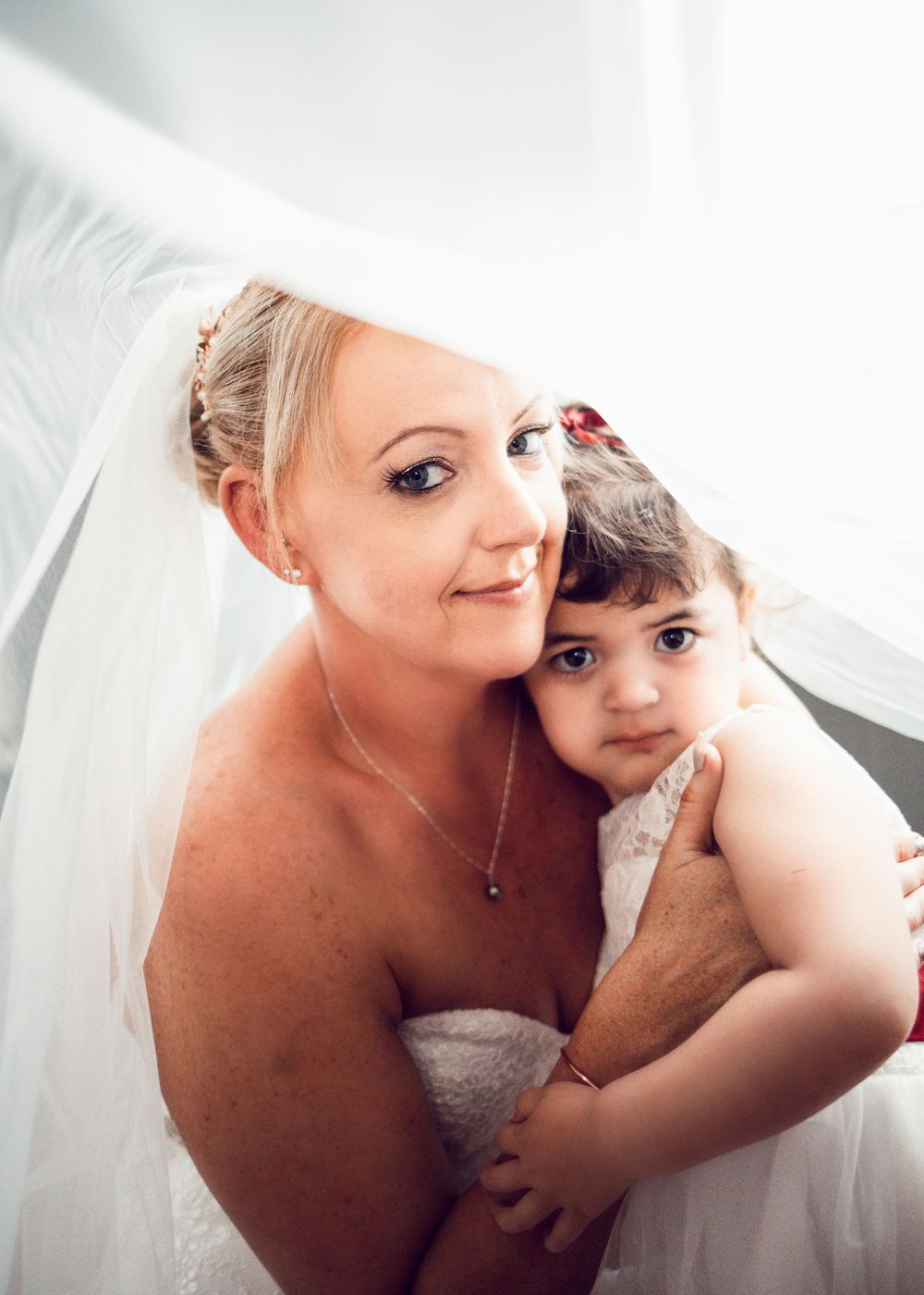 Wedding photo of bride and flower girl under the veil.