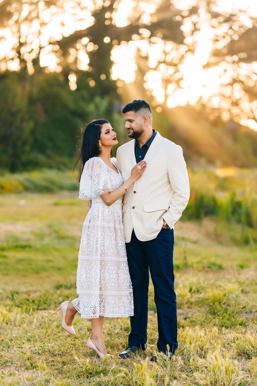 Stylish couple in white and navy outfits posing together during sunset photoshoot.