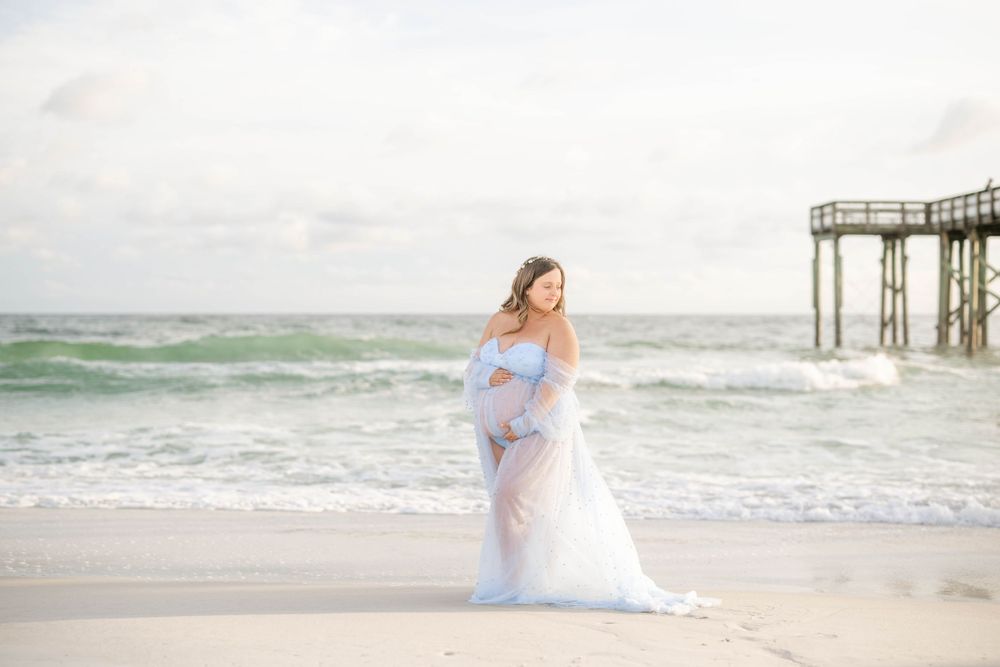 Beautiful beach maternity session with soft lighting and gentle waves in the background.