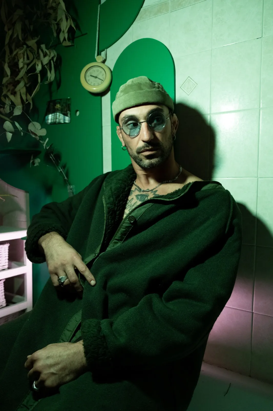 Portrait d’un homme assis dans une lumière verte, ambiance tamisée, avec un regard introspectif.