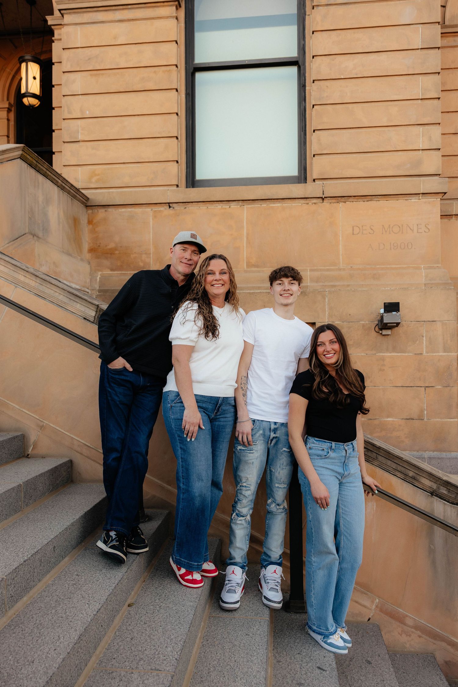 A group in coordinated casual outfits standing together on a sandstone building staircase.