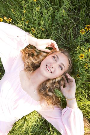 Candid moment lying in grass surrounded by yellow wildflowers on a sunny day.