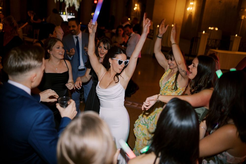 Celebratory dancing at a wedding reception features guests in formal attire enjoying the festivities at Hall of Springs in Saratoga Springs.