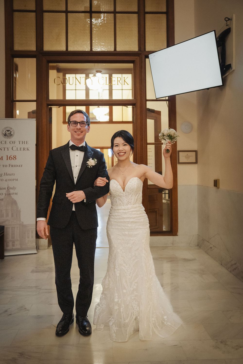 Wedding couple walks together in elegant venue with glass partitions.