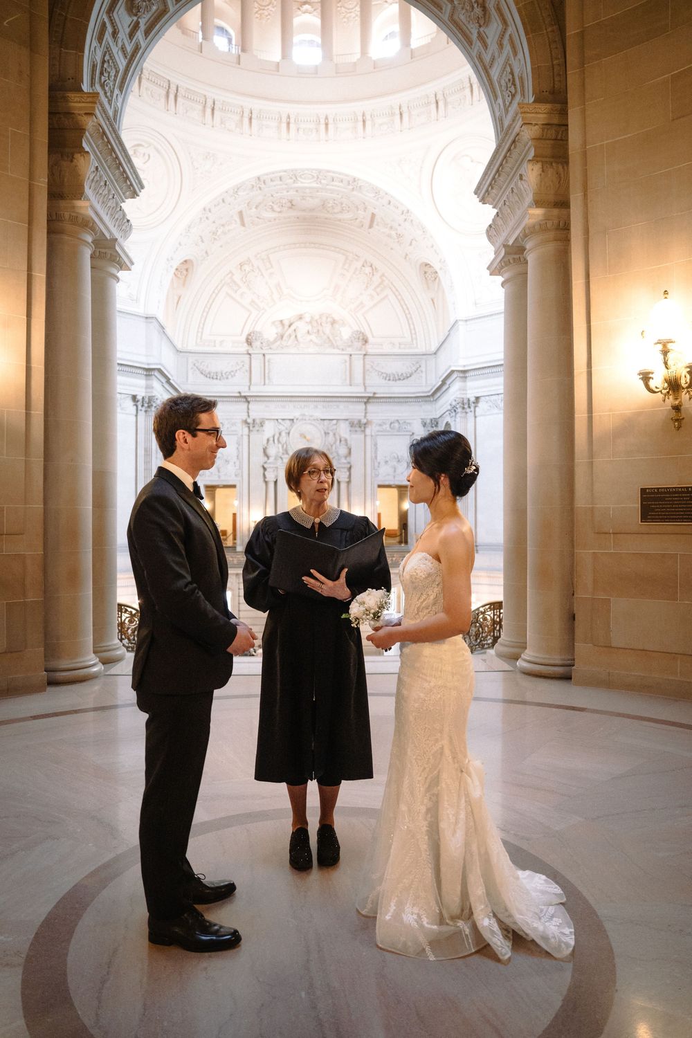 A wedding ceremony in a grand marble rotunda with ornate architectural details and columns.