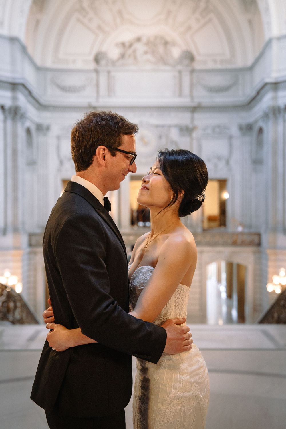 Tender moments between newlyweds in an ornate marble hall with elegant lighting.