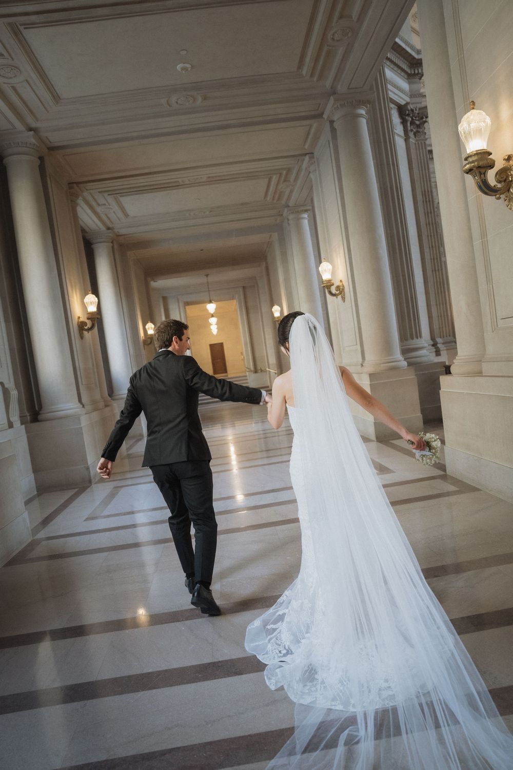 Playful wedding sequence showing couple walking through an elegant marble corridor.