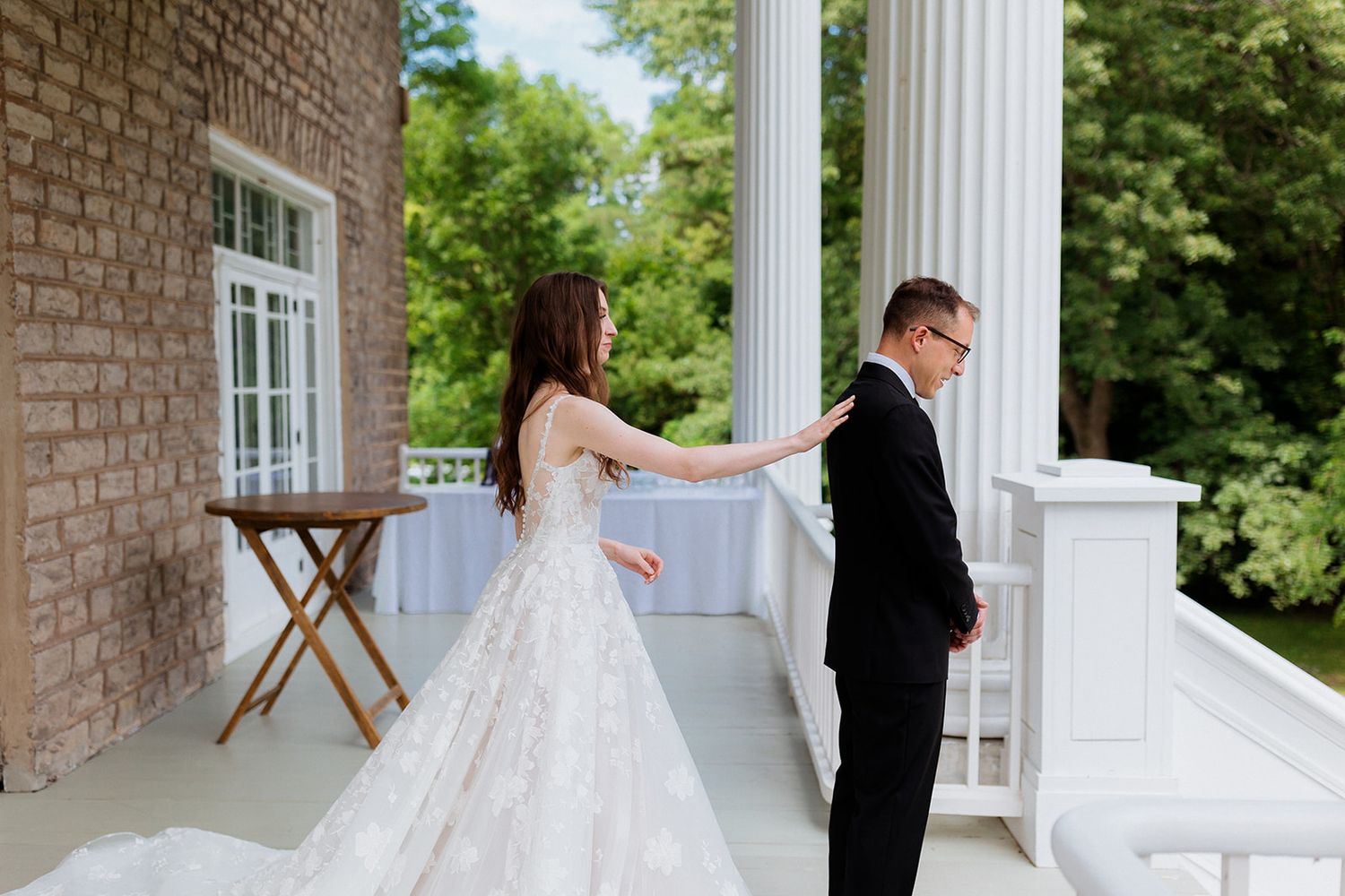 Romantic first look moment between couple on a classic white columned porch.