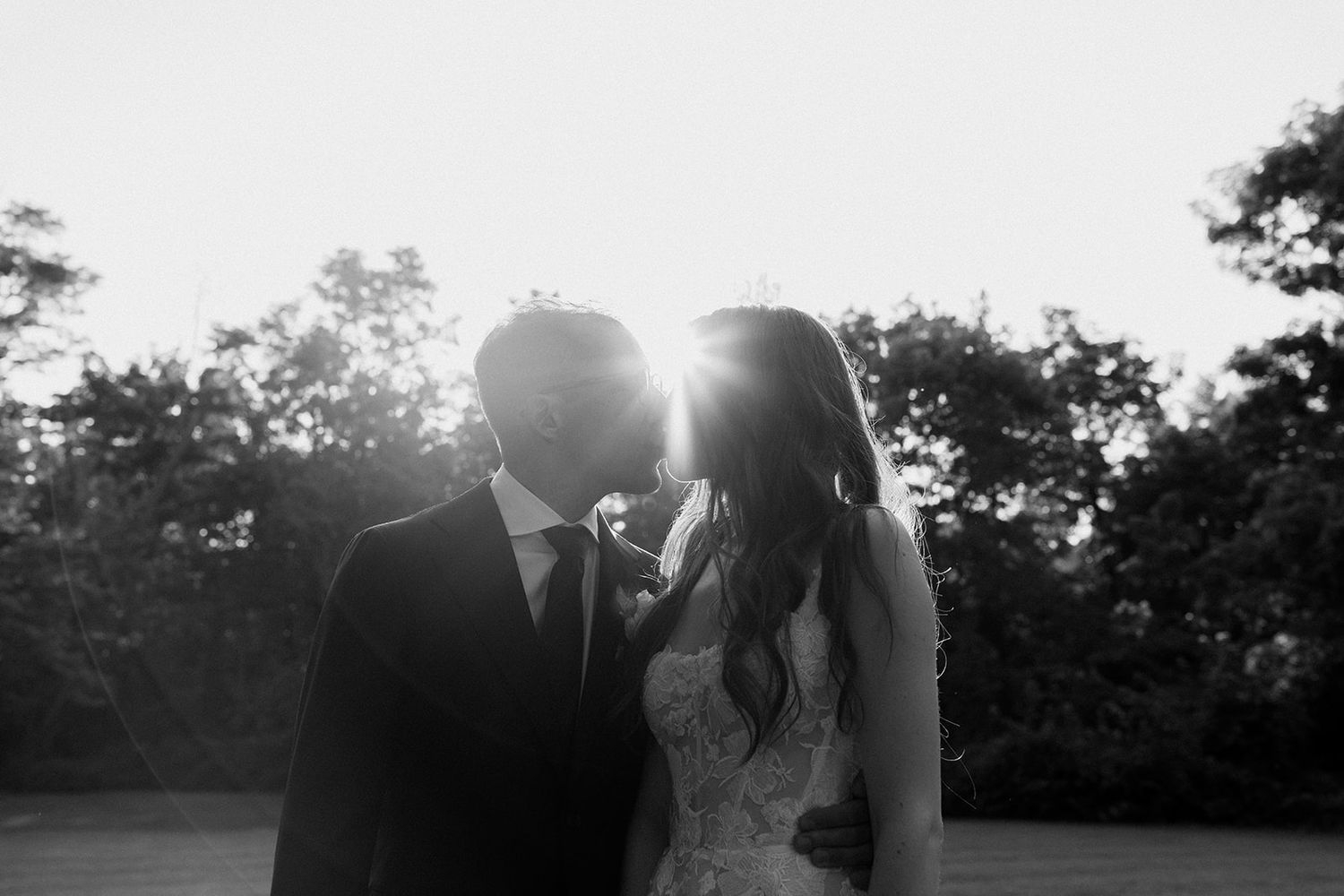 Silhouetted couple embracing in a dreamy backlit sunset scene.