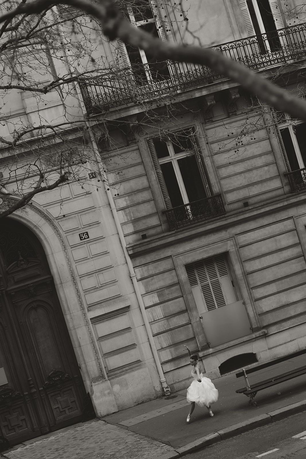 An elegant strapless wedding gown with floral lace detailing photographed against a light stone architectural backdrop.