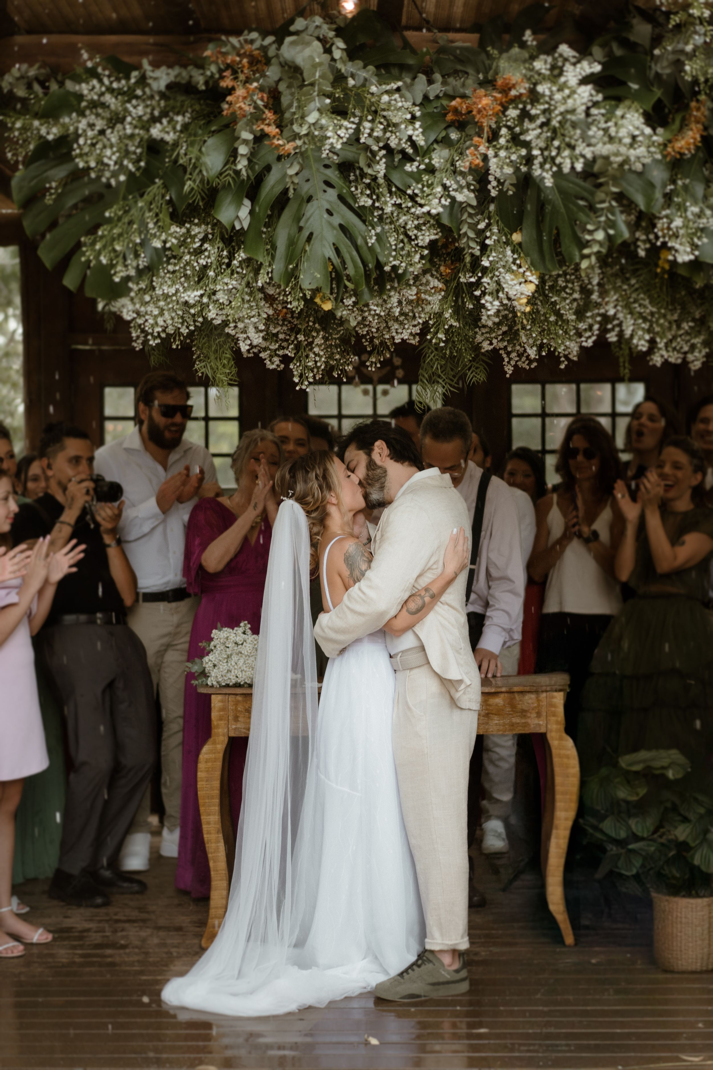 Wedding ceremony under floral decorations with guests gathered to witness the celebration.