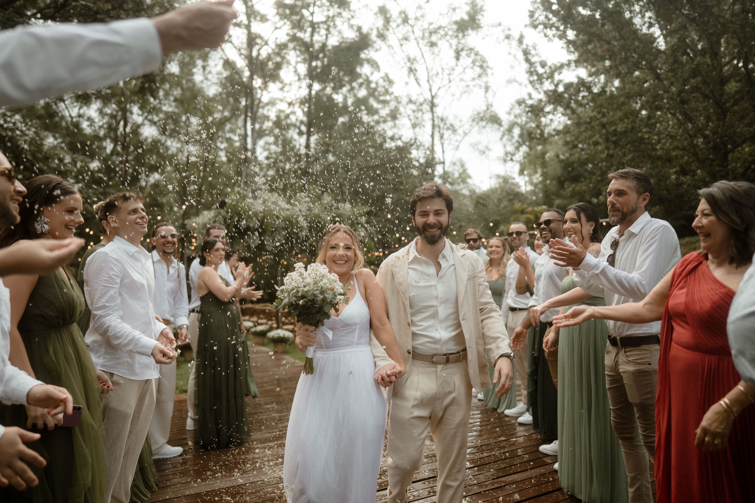 Wedding guests in casual attire celebrating outdoors during daytime.