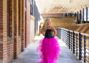 Woman in dramatic pink tulle skirt walks down brick hallway.