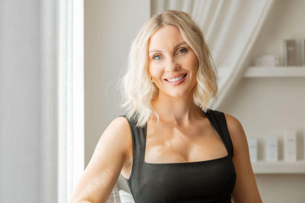 Professional lifestyle portrait in a black sleeveless top against white spa interior background.