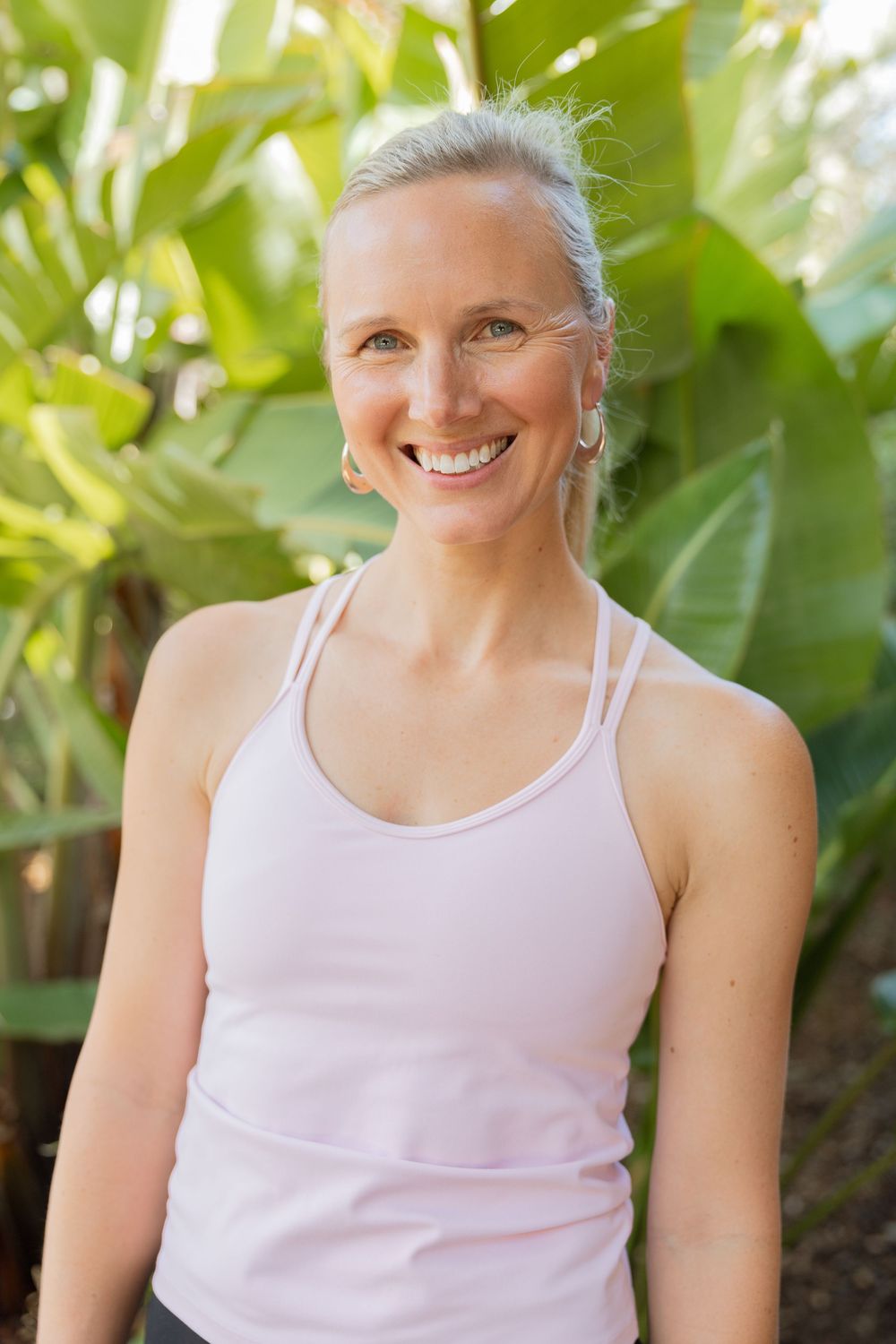 Outdoor fitness portrait with lush green foliage background.
