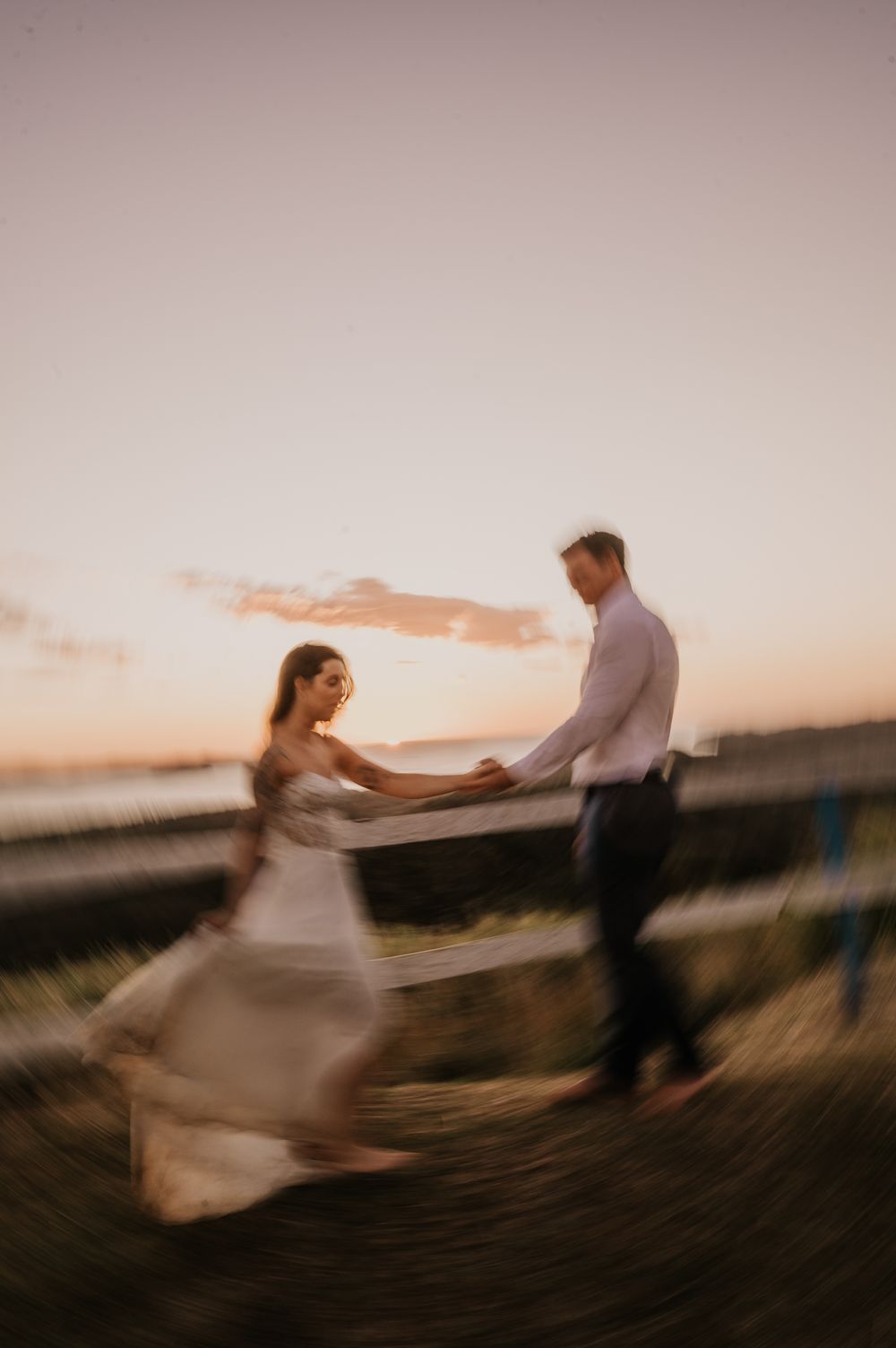 A couple dances together during sunset with motion blur creating a dreamy romantic atmosphere at their outdoor wedding.