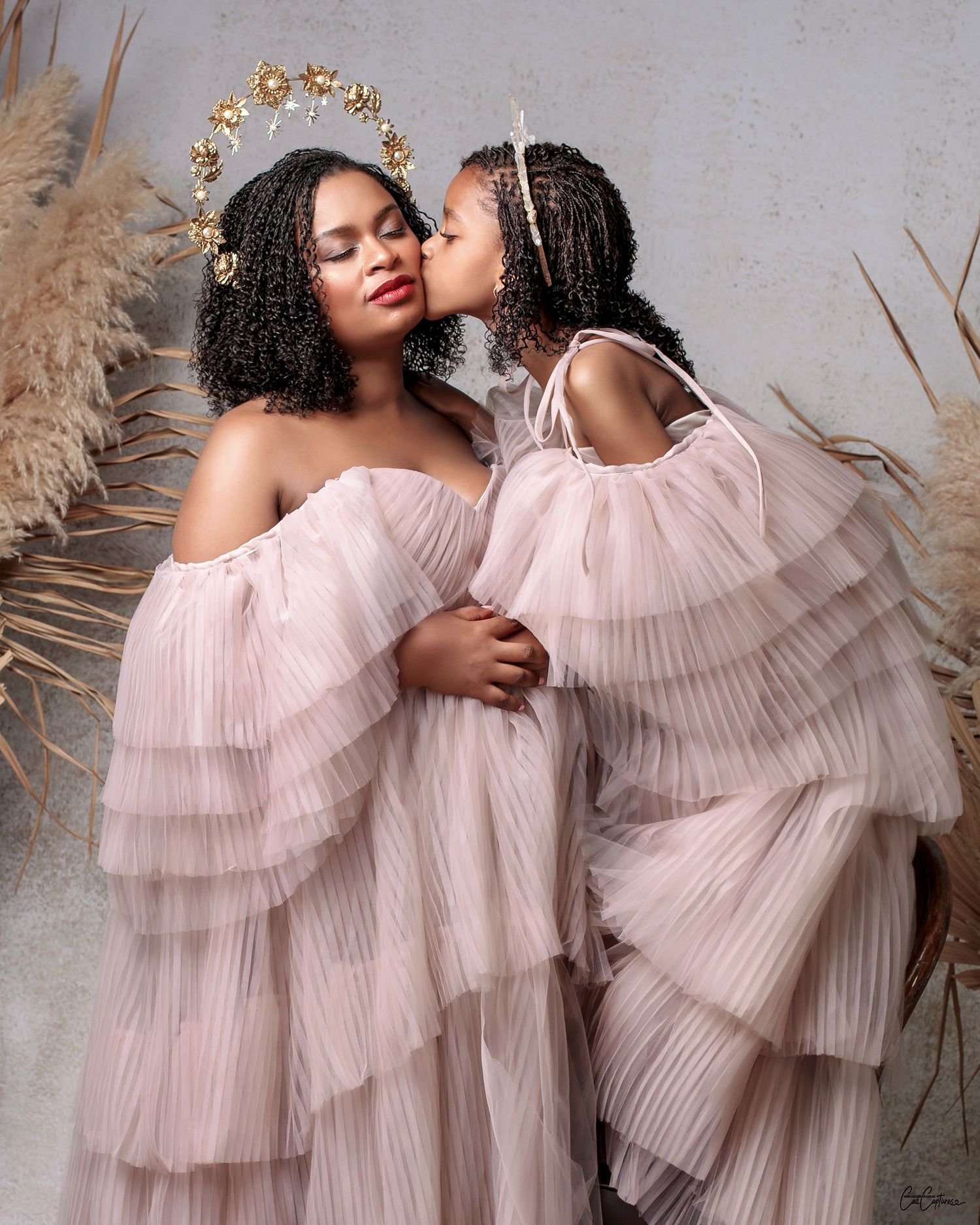 daughter kisses mother on the cheek both in matching couture gowns