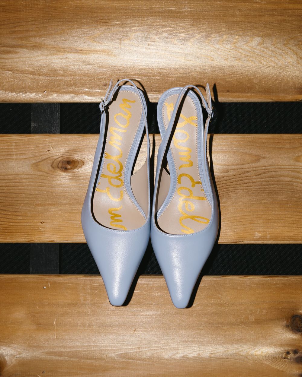 Powder blue slingback kitten heels with pointed toes rest on wooden floorboards.