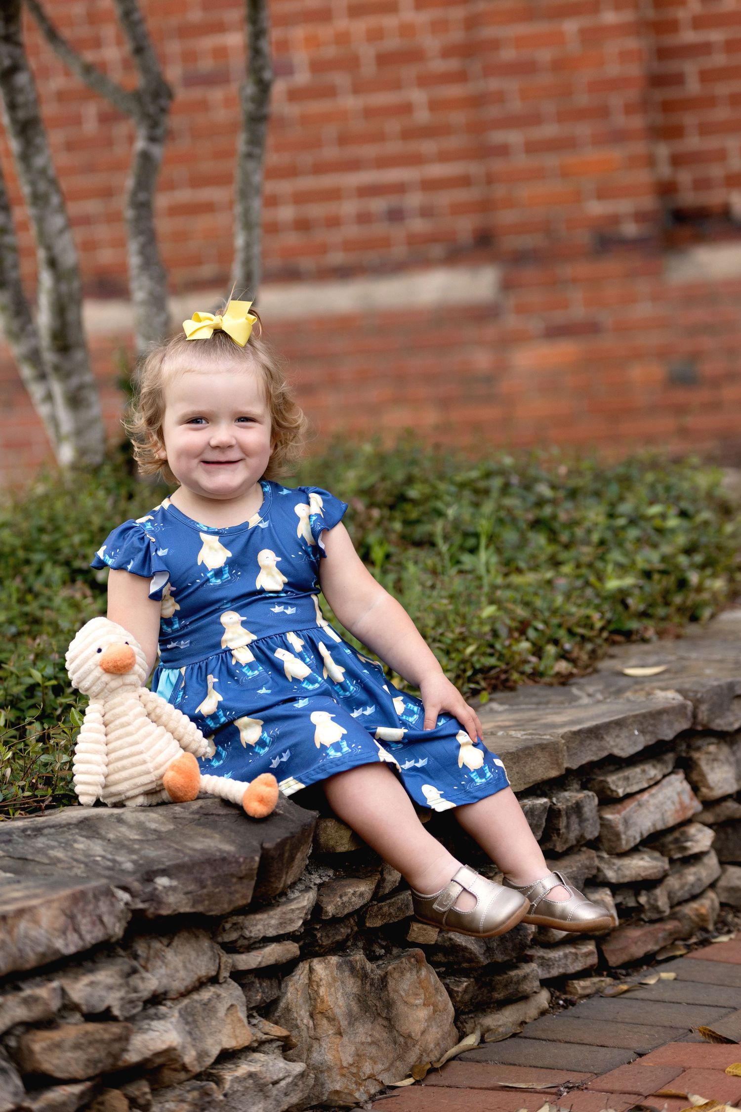 A two-year-old little girl with curls holding her duck in a duck dress. Greenville, SC newborn photographer. Easley, SC Newborn photographer