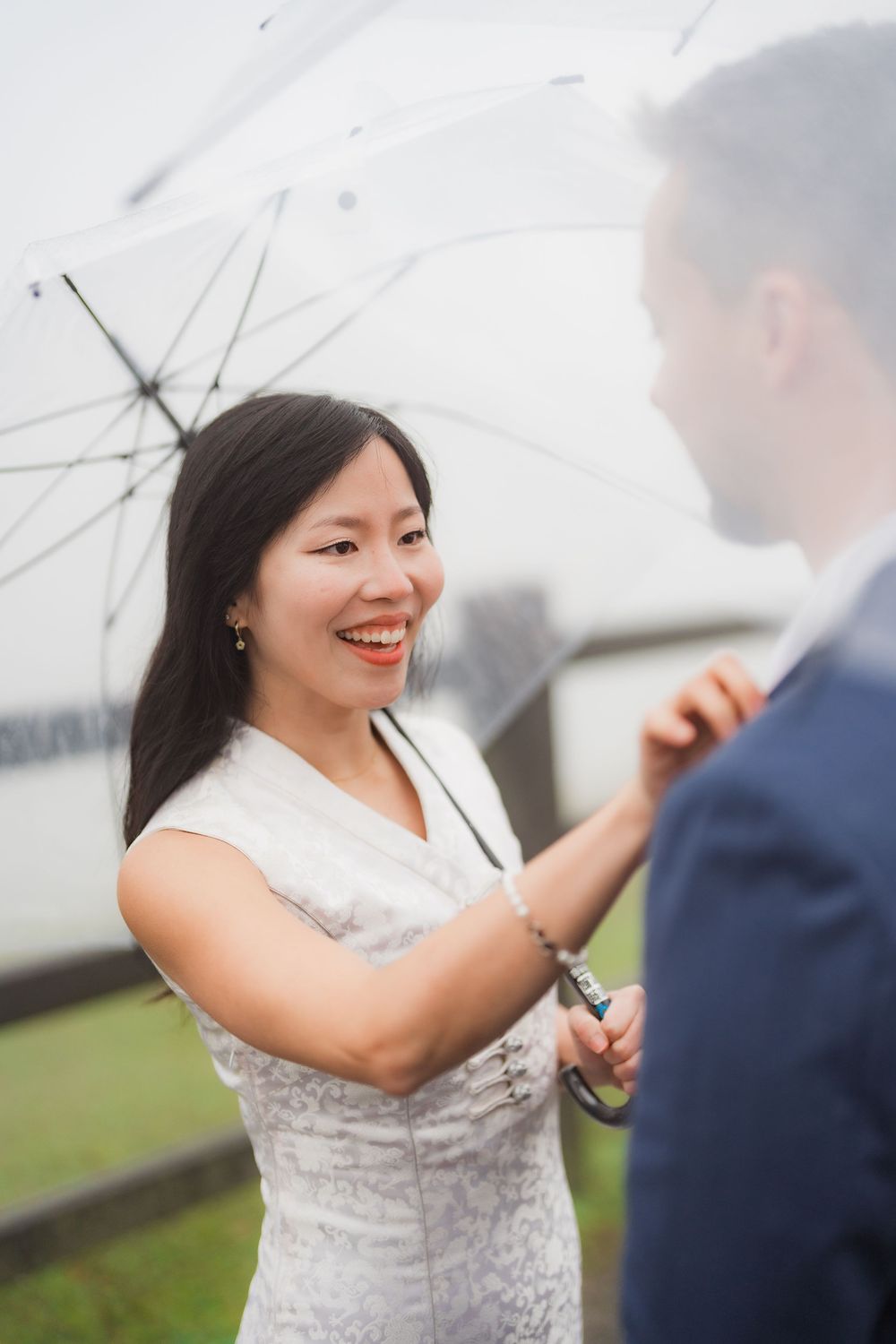 A joyful couple shares an intimate moment under a white umbrella on an overcast day at Qingtiangang in Yangmingshan National Park.