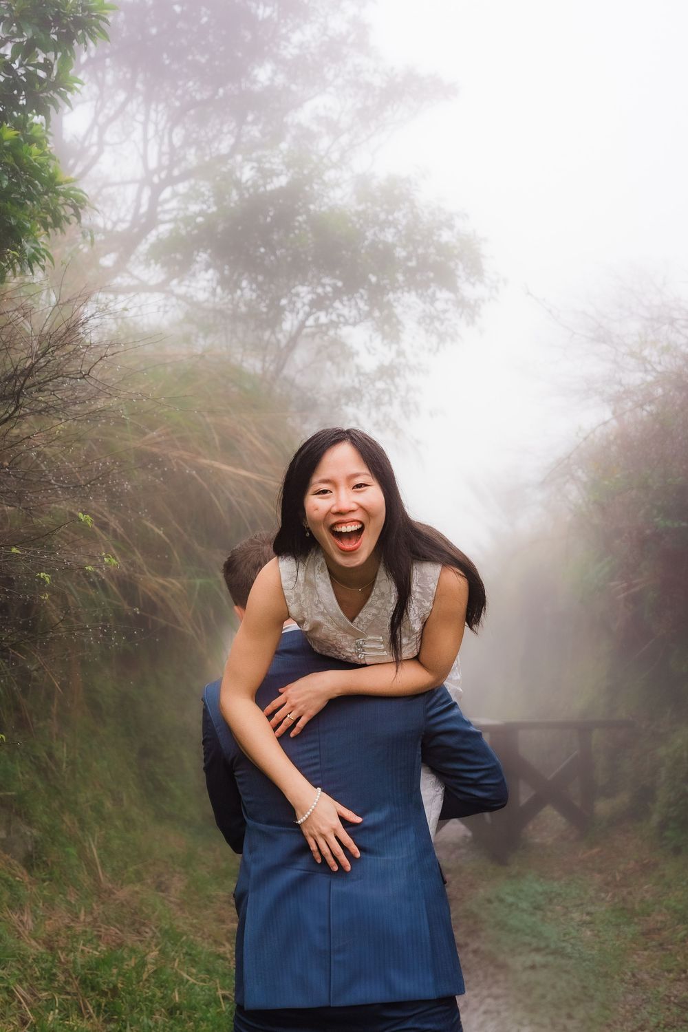 Playful outdoor photo of two people having fun together on a misty forest trail.