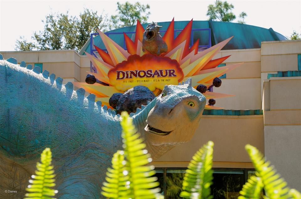 A dinosaur-themed attraction entrance sign at Disney's Animal Kingdom with ferns in the foreground.