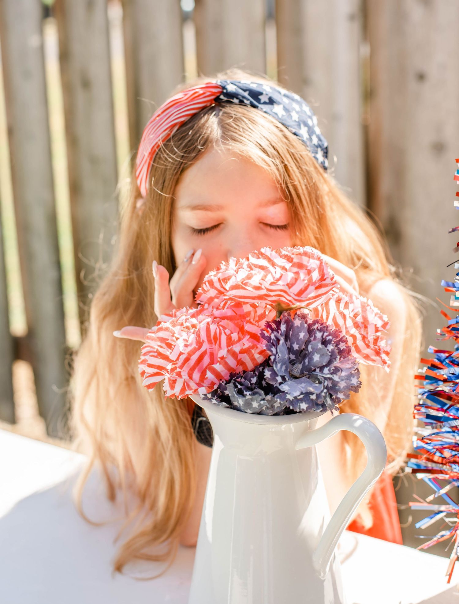 Playful patriotic themed photo with red white and blue bandana against wooden fence.