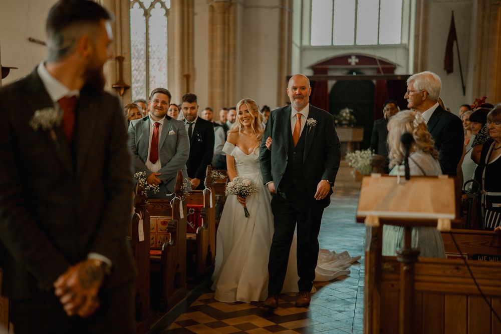 A traditional church wedding ceremony with guests watching as the couple walks down the center aisle.