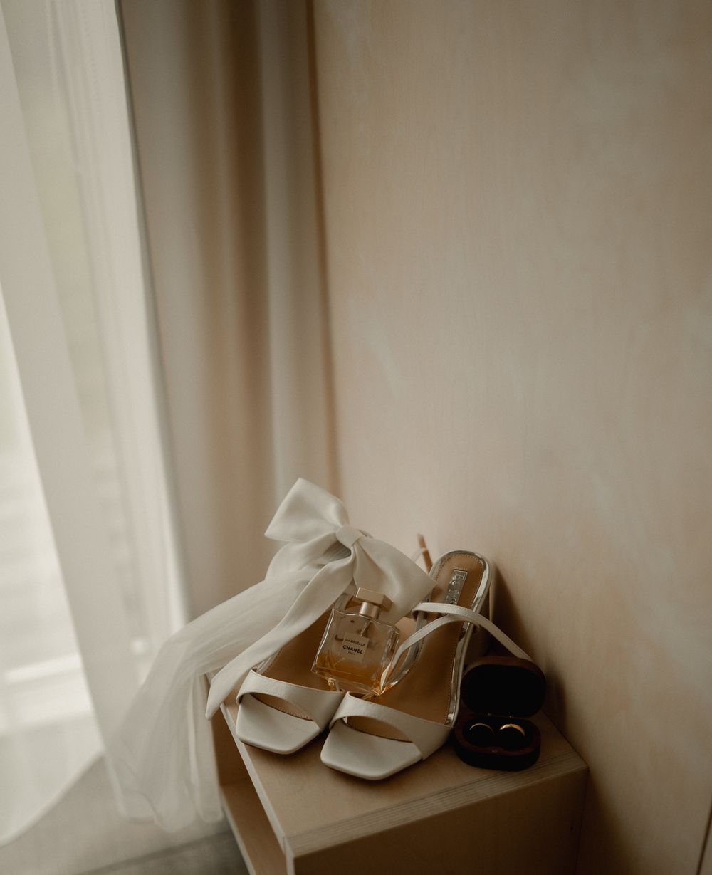 Bridal shoes and accessories artistically arranged by window in soft natural light.