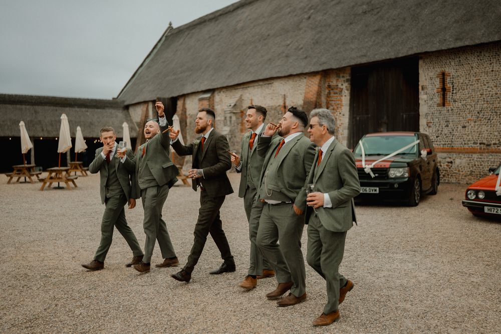 Groomsmen in matching gray suits walking and celebrating outdoors.