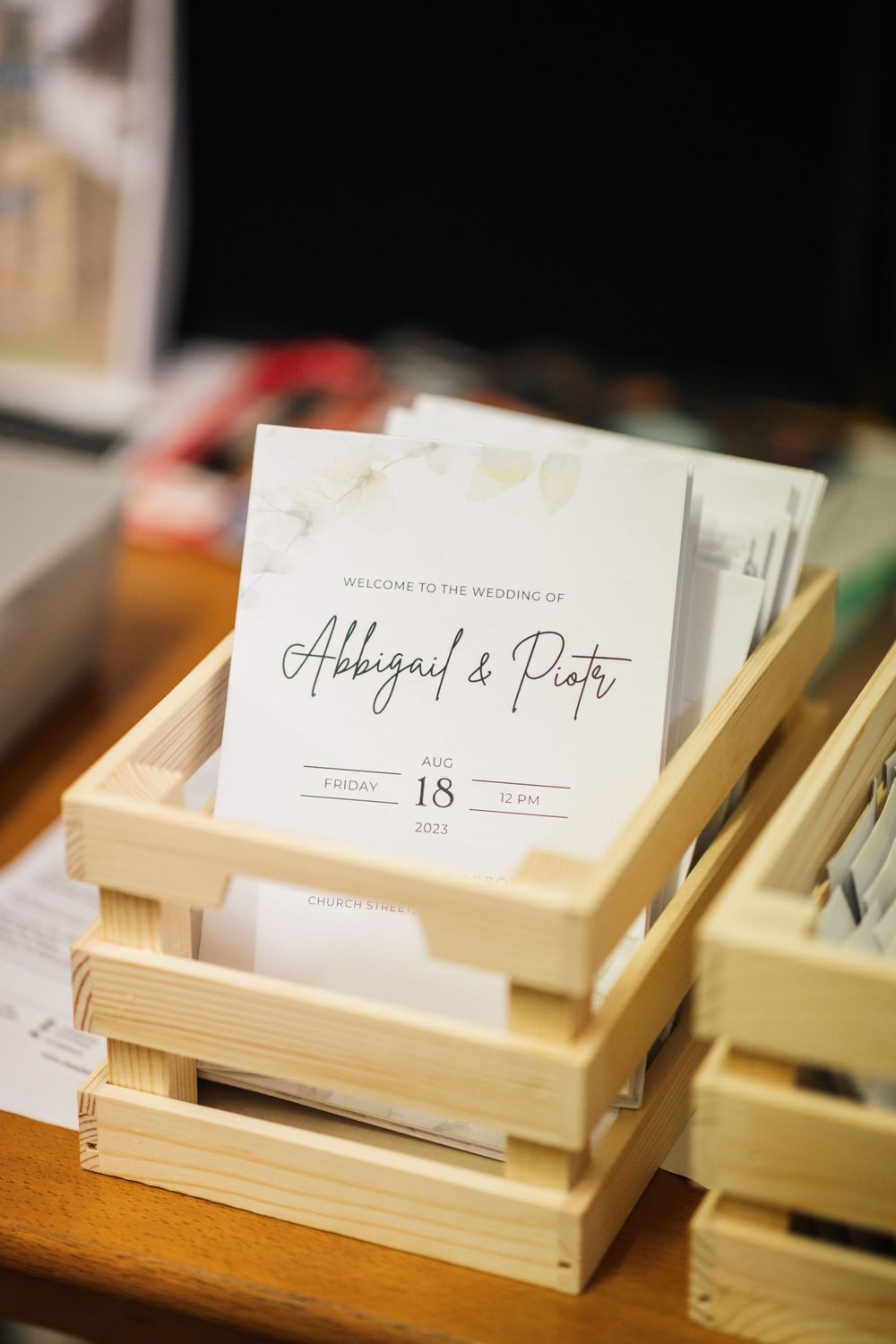 Wedding stationery displayed in wooden crates shows elegant invitation details for Abbigail's party.