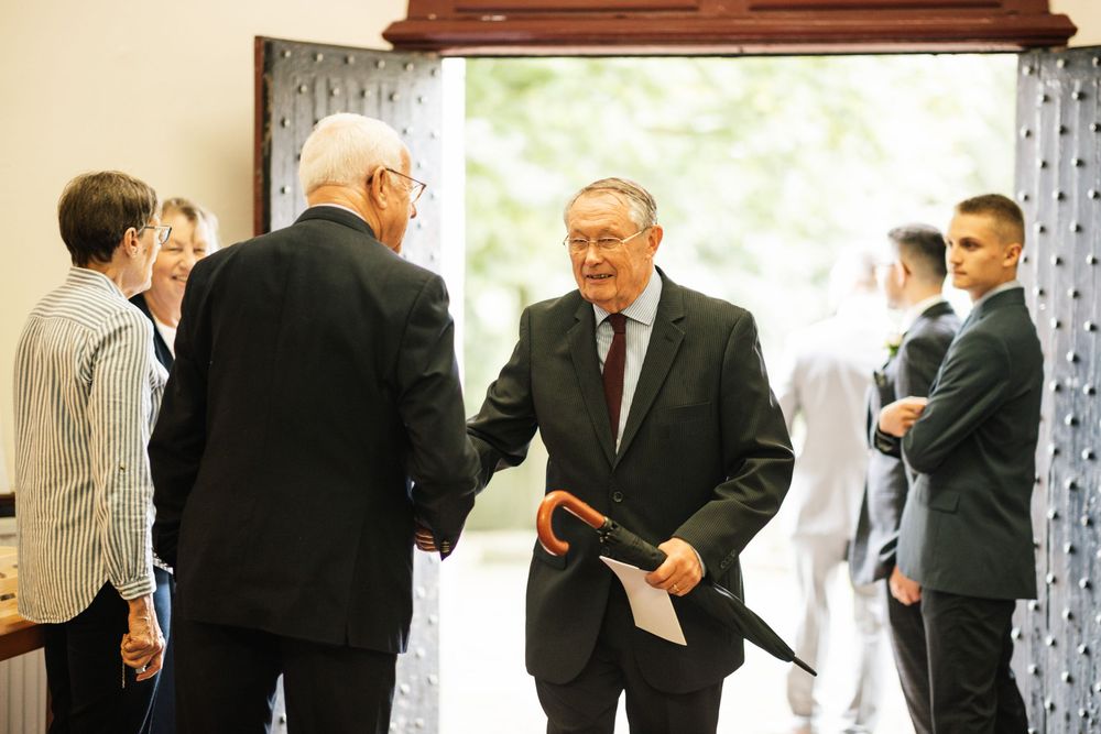 People gathered inside a building doorway having a formal conversation during what appears to be a special occasion.