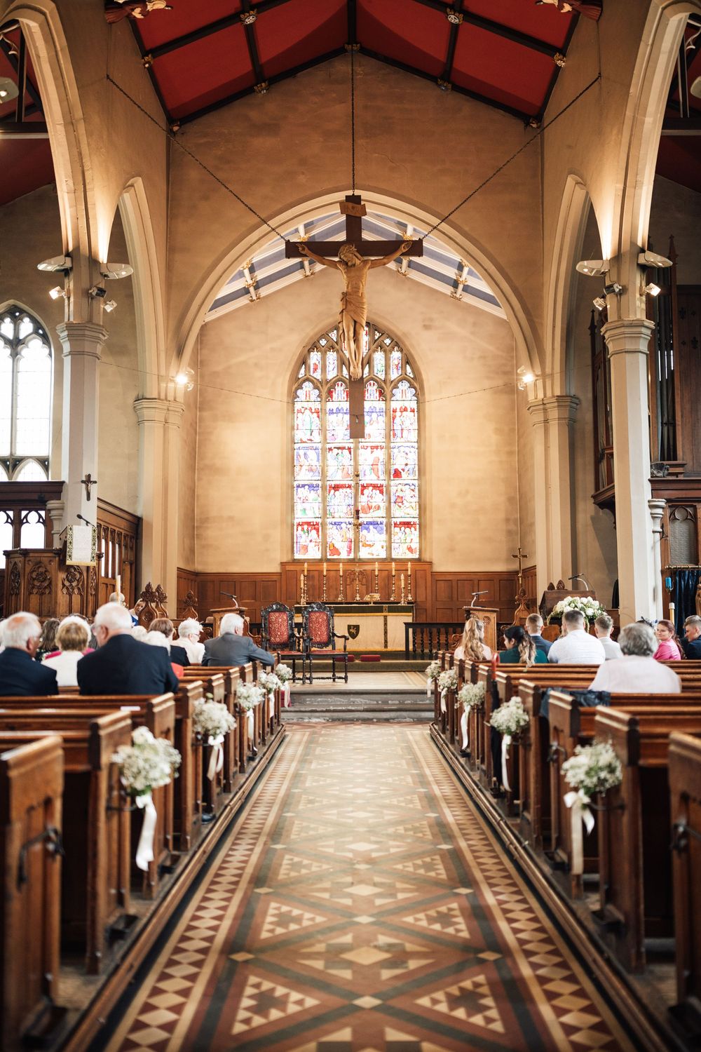 Interior of a beautiful church with stained glass windows and decorated pews for a wedding.