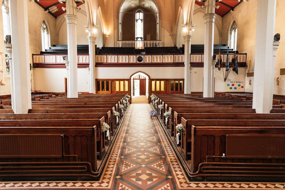 Interior view of a traditional church with wooden pews and ornate aisle leading to altar under vaulted ceiling.