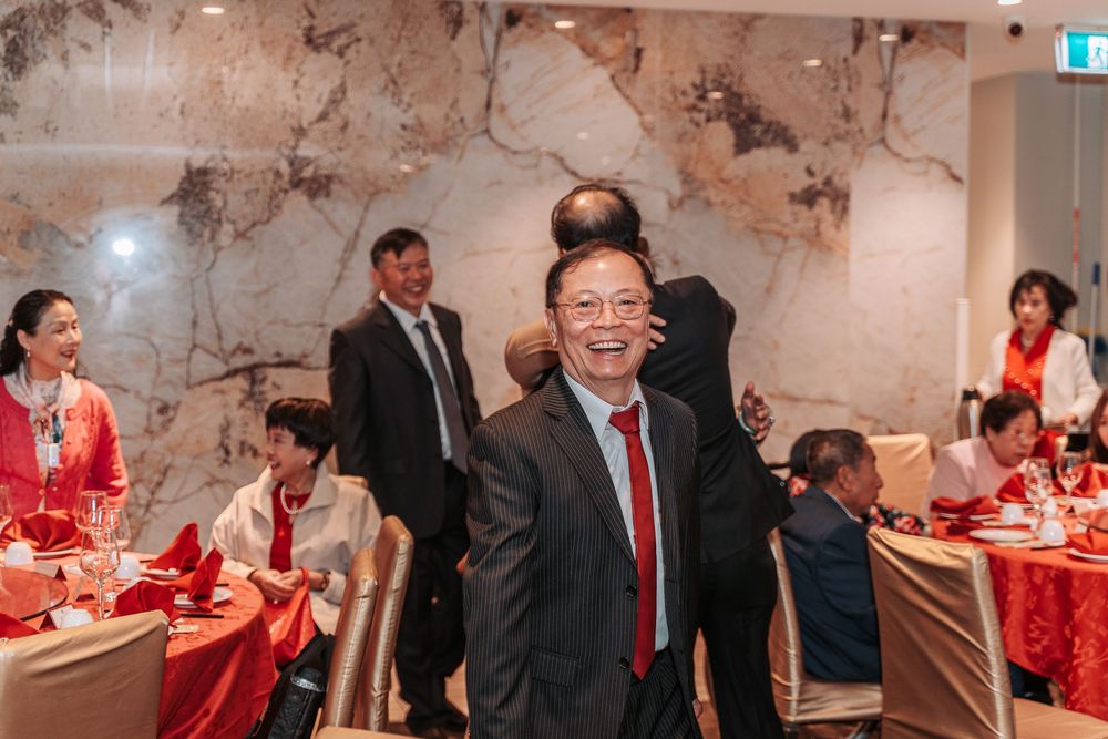 A festive wedding banquet reception with red tablecloths and decor in an elegant venue with textured stone walls.