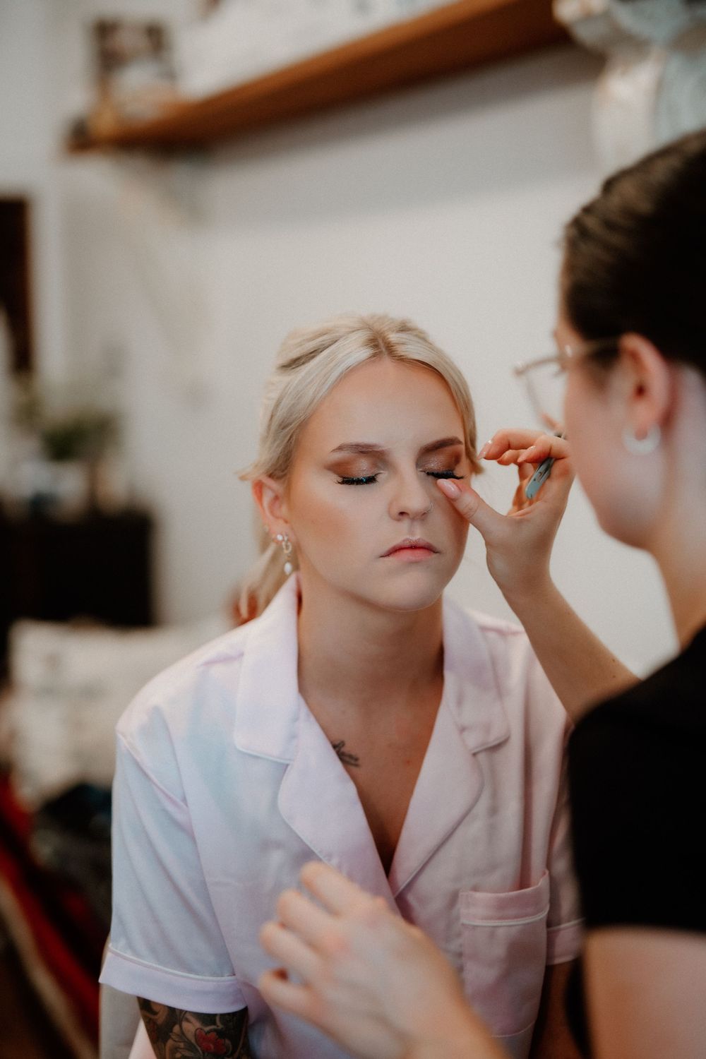 Professional makeup artist applying eye makeup to bride during wedding preparation.