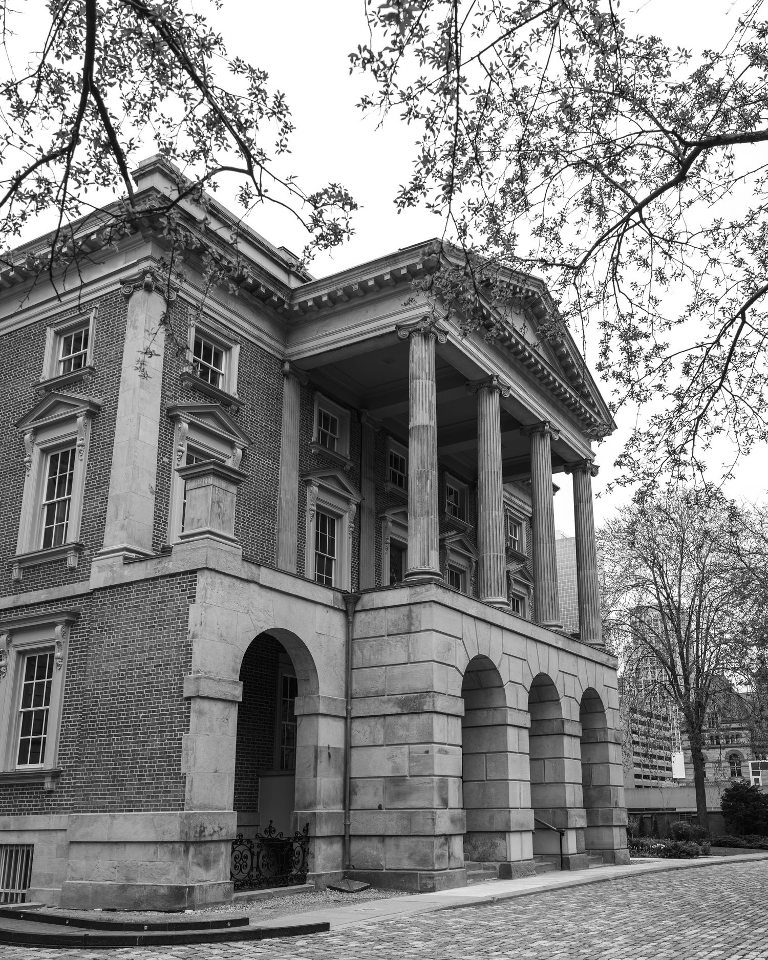 Stately historic brick building with grand neoclassical columns and arched entryway photographed in black and white.