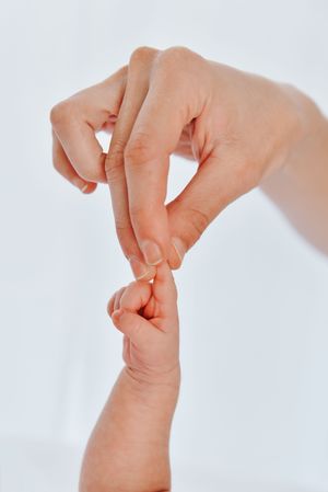 Close-up of gentle hand massage on pressure point of wrist against white background.